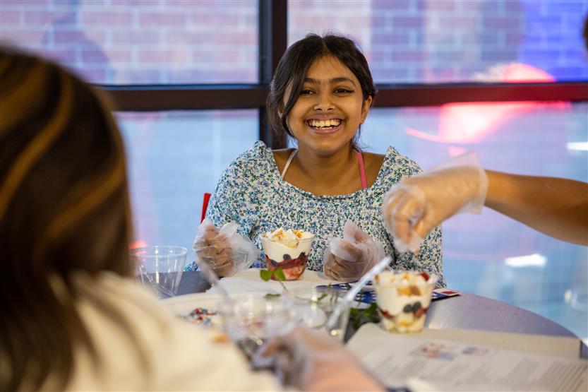 A girl smiles while making a parfait